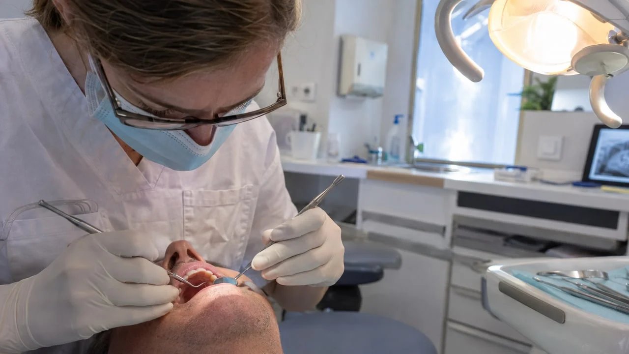Contrôle parodontal de routine, miroir et sonde tenus par des mains gantées, visage du patient hors cadre